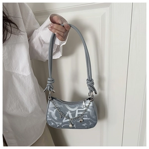 Detail of blue underarm bag with LOVE pattern, pearl chain strap, and knotting design