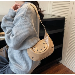 Detail of khaki crescent saddle bag with black rivet studs worn with a grey knit sweater