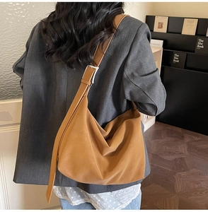 Detail of tan brown suede hobo bag with wide shoulder strap worn with a grey blazer