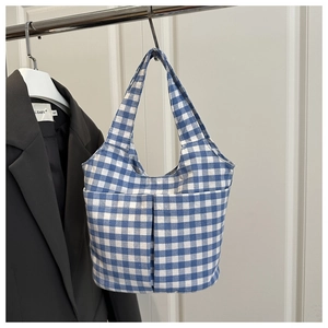 Detailed view of the blue gingham bucket bag featuring large front pockets and fabric texture