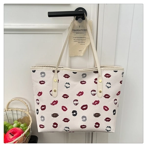 Close-up of white tote bag with red lip print hanging on a door handle