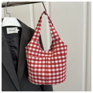 Detail of red and white checkered canvas tote bag with front pockets and twin handles