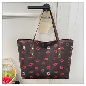 Close-up of brown tote bag with colorful lip prints and durable leather handles
