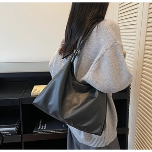 Minimalist large black hobo shoulder bag shown on model for size and drape perspective