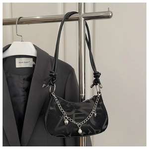 Detail of black underarm bag with abstract letter prints, silver chain and heart charm