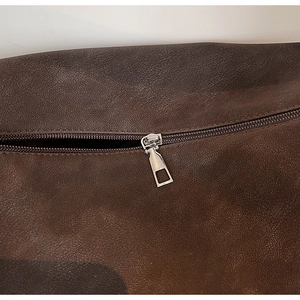 Detail of premium brown leather texture and smooth silver metal zipper on vintage tote bag