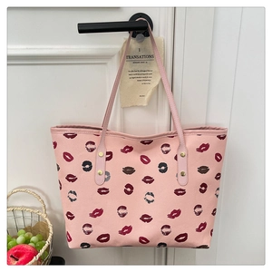 Detailed view of pink tote bag with stylish lip prints hanging on a white door