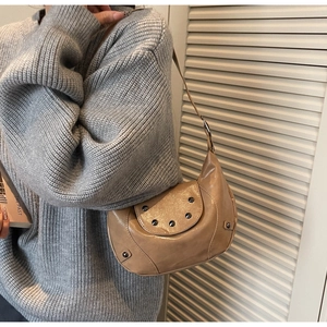 Detail of beige vintage saddle bag with silver studs and adjustable leather strap