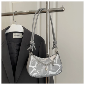 Detail of silver shoulder bag with artistic textures and star pearl charm on metal chain