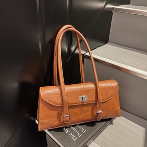 Retro brown leather underarm bag with silver square buckle on art book background