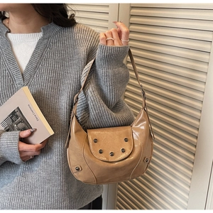 Detailed view of a vintage beige crescent saddle bag with metallic rivet accents