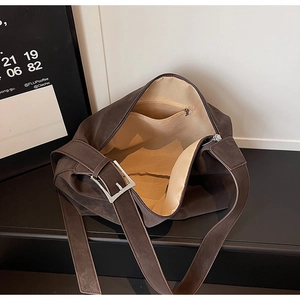 Detail view of large dark brown suede tote bag with wide strap and silver buckle