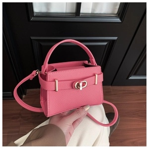 Detail der leuchtend rosa Mini-Handtasche aus genarbtem Leder mit goldener Metallschließe