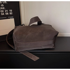 Detail of dark brown matte leather tote bag with wide strap and adjustable shoulder belt