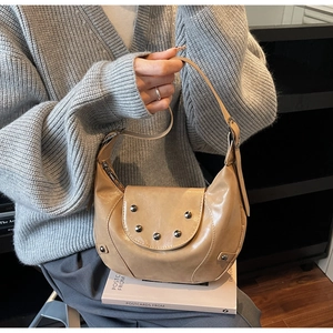 Detail of camel crescent bag with silver studs and adjustable strap on a model
