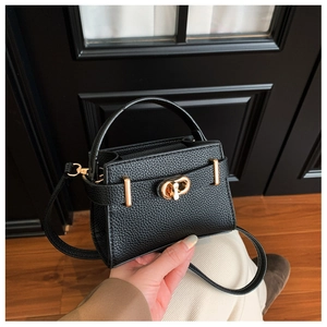 Detail der schwarzen Mini-Handtasche aus genarbtem Leder mit elegantem goldfarbenem Drehverschluss