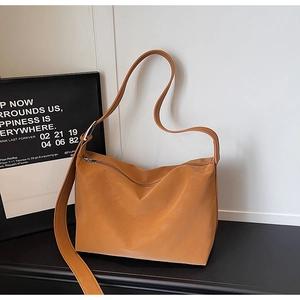 Detail view of tan leather tote bag with wide adjustable shoulder strap and silver zipper