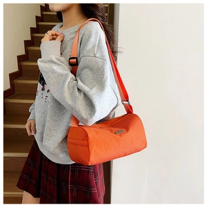 Close-up of orange checkered cylindrical nylon bag with adjustable strap and metal logo