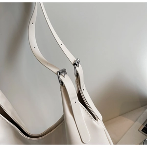 Detail of silver metal buckle and reinforced stitching on the beige tote bag strap