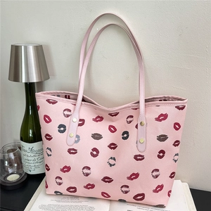 Pink tote bag with lip print patterns and golden rivets on long shoulder straps