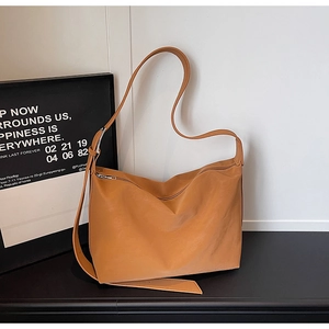 Detail view of ginger yellow leather hobo bag with wide adjustable strap on black desk