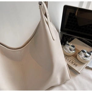Detail of minimalist cream tote bag with adjustable strap on a modern office desk