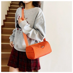 Detail of orange plaid nylon bucket bag with adjustable strap and metal logo plaque