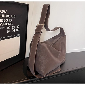 Detail of wide shoulder strap with silver metal buckle on a brown leather tote bag