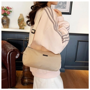 Detail of checkered texture and metal logo plate on beige nylon crossbody bag