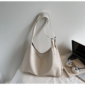 Detail of cream minimalist tote bag showing silver buckles and soft leather texture