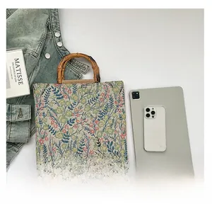 Floral canvas tote bag with bamboo handles shown flat lay with daily essentials