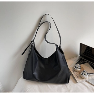 Detail of minimalist black hobo bag with adjustable strap and matte finish textures
