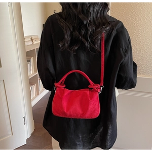 Close-up of red suede cloud bag showing soft texture and crossbody strap details