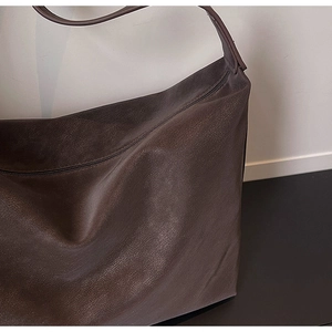 Macro shot of dark brown pebbled leather texture on a spacious crossbody tote bag