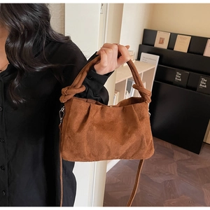 Detail of dark brown suede cloud bag with pleated texture and stylish knot handle