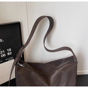Detail of coffee brown leather tote bag showing smooth matte texture and silver buckle