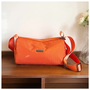 Macro detail of bright orange plaid nylon gym bag with metal logo and zipper closure