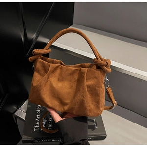 Detail of a brown suede cloud bag featuring a ruched design and a knotted handle