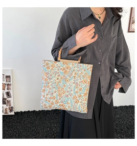 Detailed close-up of a floral tote bag featuring rustic bamboo handles and woven fabric