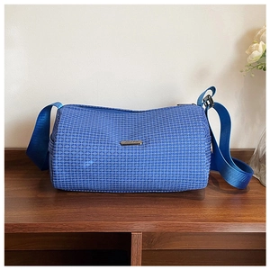 Close-up of blue geometric plaid duffel bag with metallic logo on a wooden surface