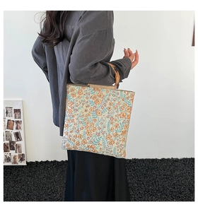 Floral jacquard tote bag with bamboo handles shown being worn by a model in a side view