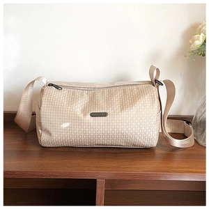 Detail view of champagne gold crossbody bag with geometric grid texture and metal logo
