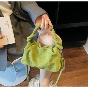 Detail of green suede pleated cloud bag with knotted handle and shoulder strap