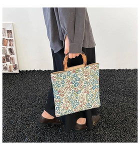 Detail view of a floral tote bag with vintage bamboo handles and colorful fabric patterns