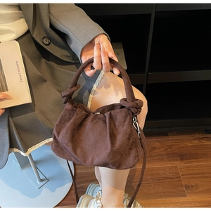 Detail of dark brown suede cloud bag showing textured pleats and adjustable shoulder strap