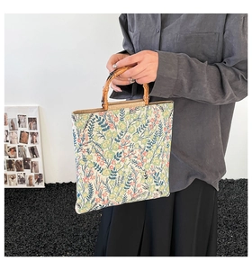 Detail of floral tote bag featuring a natural bamboo handle and woven texture fabric