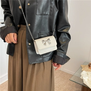 Détail du mini sac bandoulière blanc avec un nœud argenté et une bandoulière chaîne