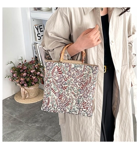 Close-up of a floral embroidered tote bag with a natural bamboo handle and metal hardware