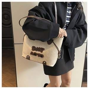 Close-up of cream tote bag with dark brown straps and plush letter applique decoration