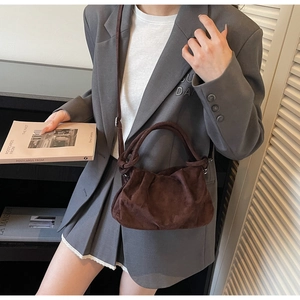Detail of dark brown suede cloud bag with twisted handle and long shoulder strap